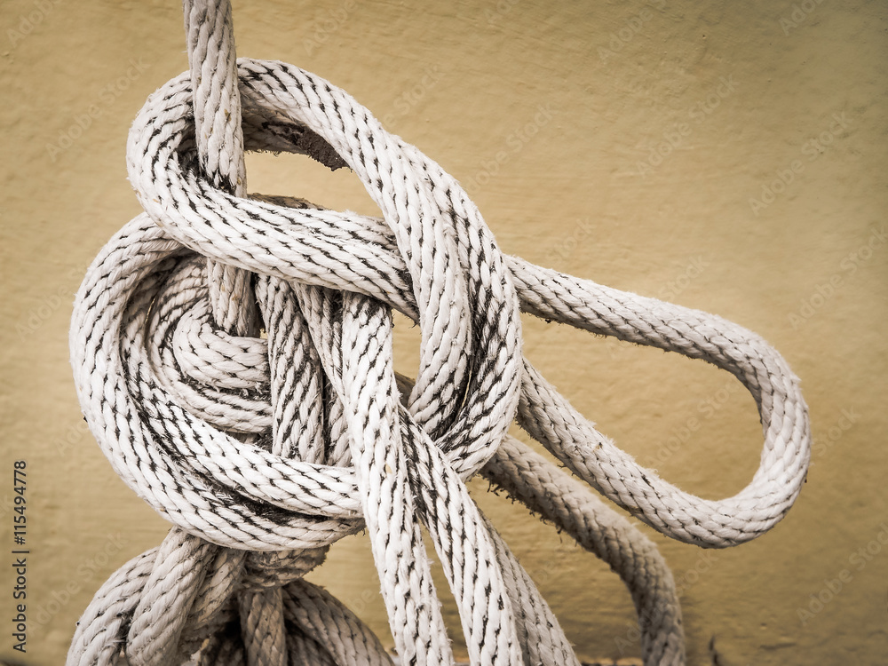 Close up of white rope And Knot on yellow cement wall Close up of white rope And Knot on yellow cement wall