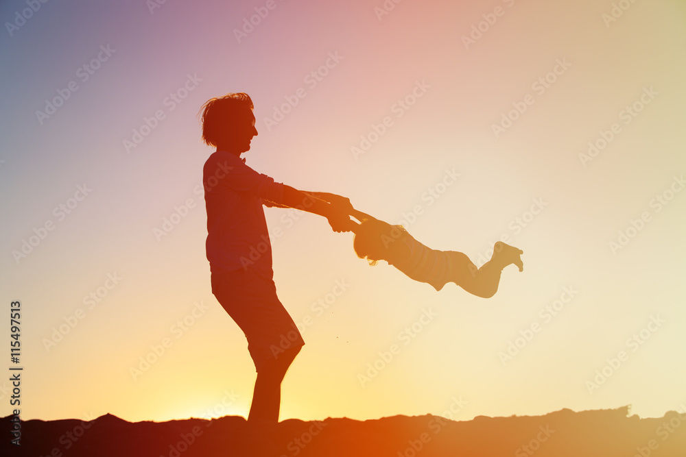 Father and little daughter silhouettes play at sunset Father and little daughter silhouettes play at sunset