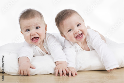 smiling happy twin baby girls on tummy