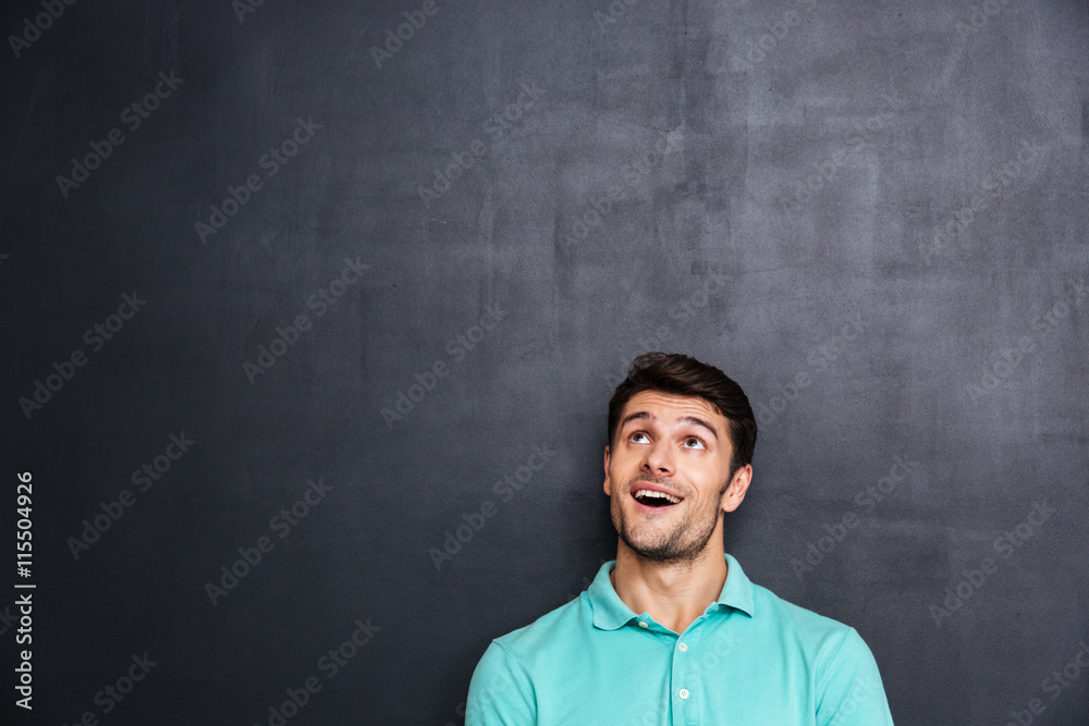 Wondered happy young man with mouth opened looking up