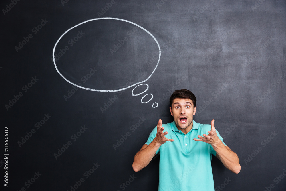 Amazed astonished young man standing over chalkboard background