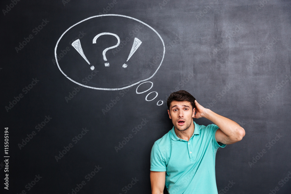 Puzzled confuzed young man over chalkboard background