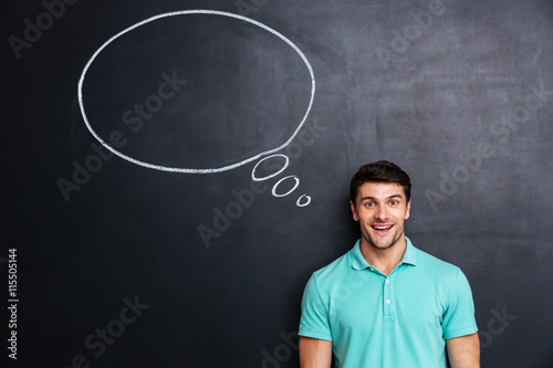 Cheerful man standing over chalkboard background with blank speech bubble