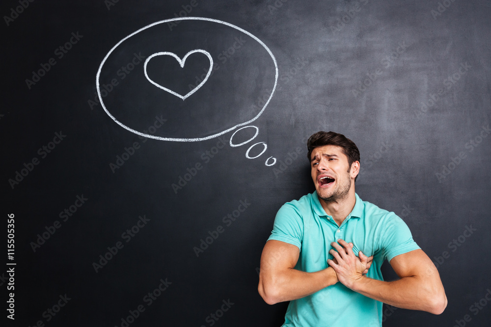 Unhappy embarrassed man crying and having heartache over chalkboard