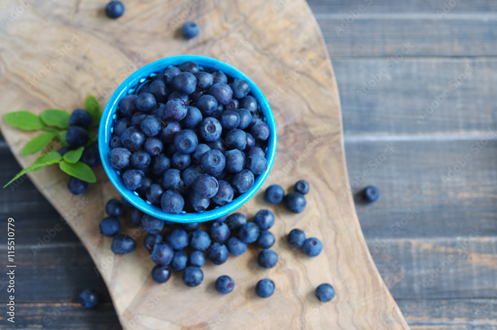 Berries of ripe juicy bilberry in a blue small plate on a wooden table. Berries of ripe juicy bilberry in a blue small plate on a wooden table.