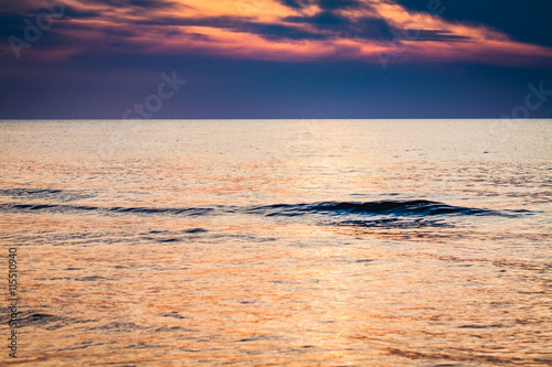 Single small wave on the surface of the calm sea at sunset.