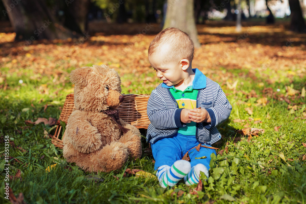 little boy playing with a bear in the autumn park little boy playing with a bear in the autumn park