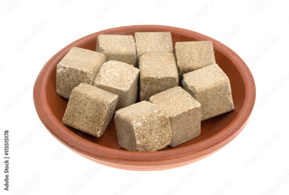 Beef flavored bouillon cubes in a bowl side view isolated on a white background.