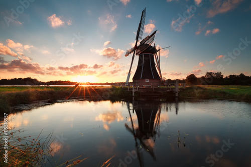 Dutch windmill by lake at sun down