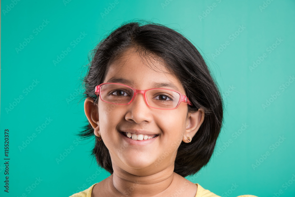 Happy little indian girl smiling while wearing glasses, green background,  indian small girl wearing glass, asian small girl and glasses, 10 year old  girl, extreme closeup or close up Stock Photo