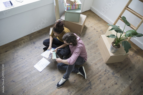 Couple sitting on floor of new flat choosing from color samples photo