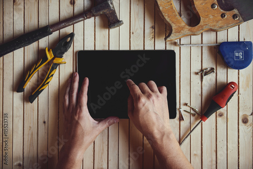 Fotografi Close-up of male hands touching screen of digital computer pc on worktable with instruments