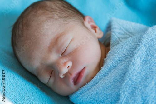 Newborn baby Asia while sleeping covered with blue cloth