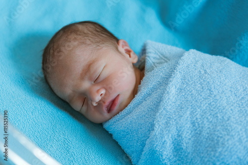 Newborn baby Asia while sleeping covered with blue cloth
