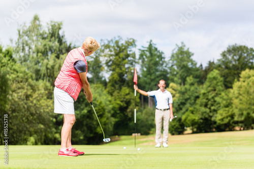 Senior Frau übt Golf mit Golflehrer auf dem Green