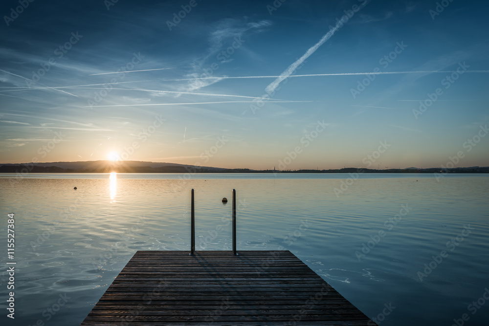 Naklejka premium Jump. Relaxing quiet evening on the lake. Setting sun is reflected in water. Switzerland.