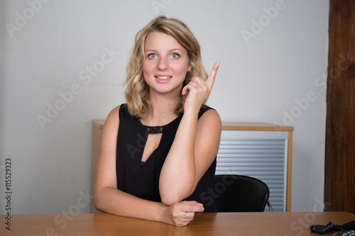 Young business woman sitting behind the desk and having idea