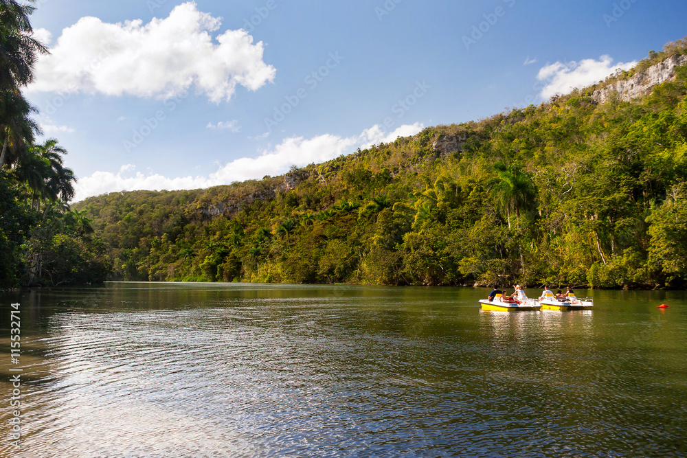 Obraz premium Tourists on catamarans float down the river between wooded mountains. Cuba.