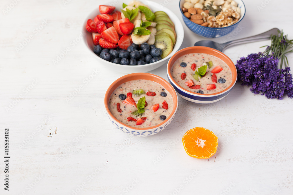 Vegan fruit and berry smoothie breakfast, topped with blueberries, strawberries and mint, seved with fruits, berries and nuts, selective focus Vegan fruit and berry smoothie breakfast, topped with blueberries, strawberries and mint, seved with fruits, berries and nuts, selective focus