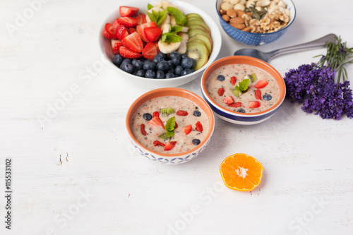 Vegan fruit and berry smoothie breakfast, topped with blueberries, strawberries and mint, seved with fruits, berries and nuts, selective focus