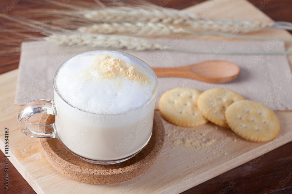 Hot milk with biscuits on wooden plate on wooden table for break Hot milk with biscuits on wooden plate on wooden table for break