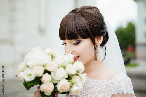 Beautiful smiling bride portrait near architecture with flowers