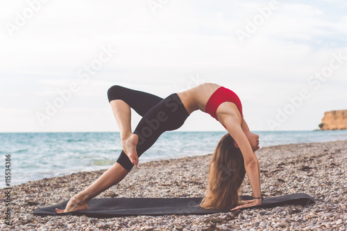 Young girl doing yoga on the beach