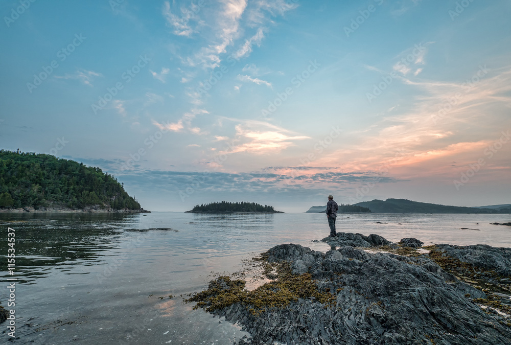 Fototapeta premium Man Standing on Rock Looking Out Over St. Lawrence River in Queb