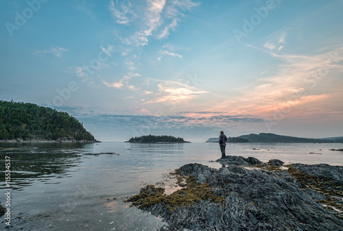 Man Standing on Rock Looking Out Over St. Lawrence River in Queb photo