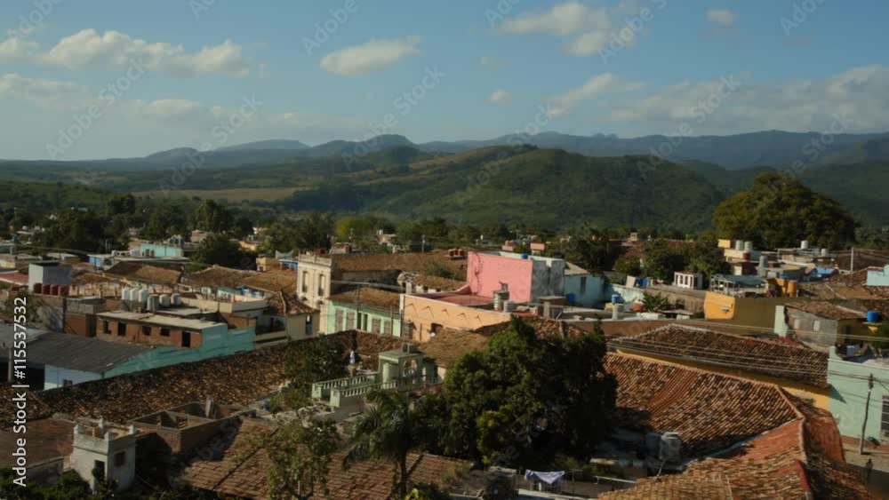 Schwenk über die Stadt Trinidad auf Kuba aus erhöhter Position als Eröffnungsszene. Bei sonnigem Wetter im Hintergrund eine Bergkette. Clip endet mit Sicht auf Stadtkern mit Kirche und bewegter Palme. Schwenk über die Stadt Trinidad auf Kuba aus erhöhter Position als Eröffnungsszene. Bei sonnigem Wetter im Hintergrund eine Bergkette. Clip endet mit Sicht auf Stadtkern mit Kirche und bewegter Palme.