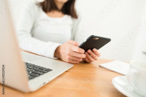 Woman using cellphone on her working desk