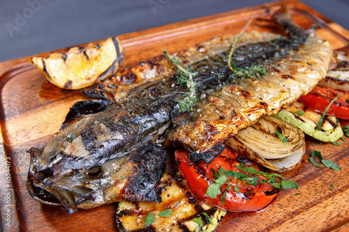 Baked mackerel with vegetables on a wooden board