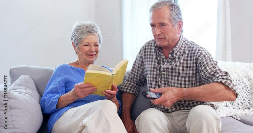 Cute elderly couple reading or watching TV Cute elderly couple reading or watching TV