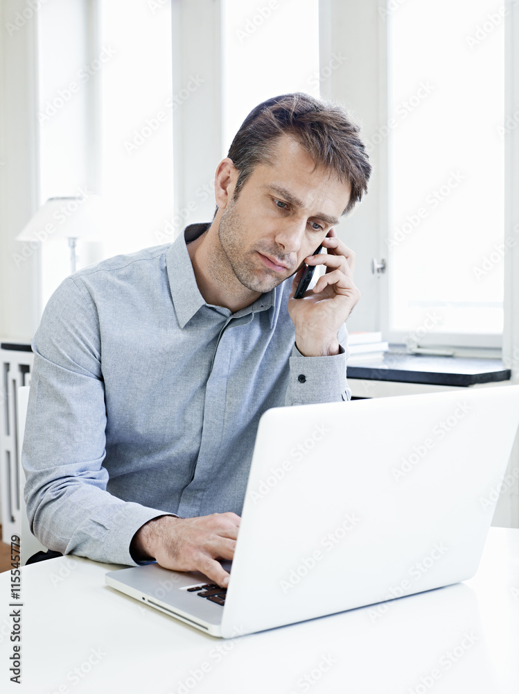 Mature businessman using mobile phone and laptop Mature businessman using mobile phone and laptop