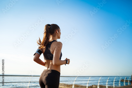 Obraz na plátne Picture of young attractive fitness girl jogging with sea on background