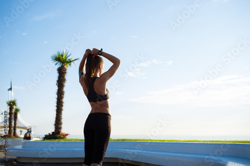 Picture of young beautiful fitness girl makes sport exercises with sea on background