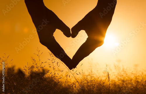 Hand shaped heart against a beautiful sunset. 