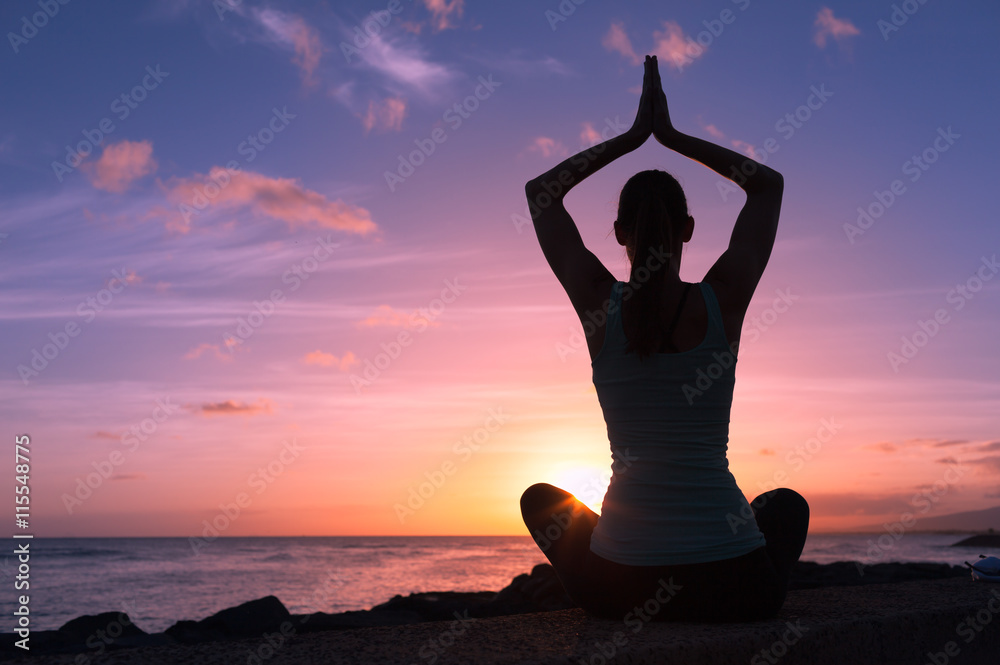 Young healthy woman practicing yoga on the beach at sunset

