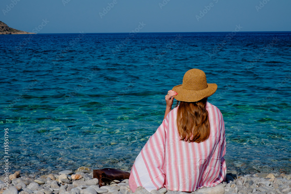 Young girl in a straw hat on the beach enjoying the beautiful views