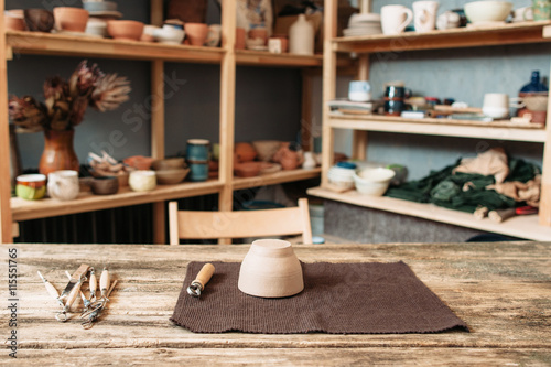 Potter workplace with necessary tools at studio, clay bowl on wooden table, ready for work