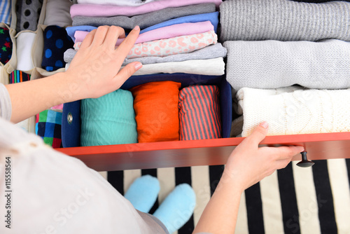 Woman folding clothes into chest of drawers closeup