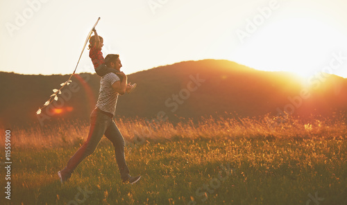 happy family father and child run on meadow with a kite in summe photo