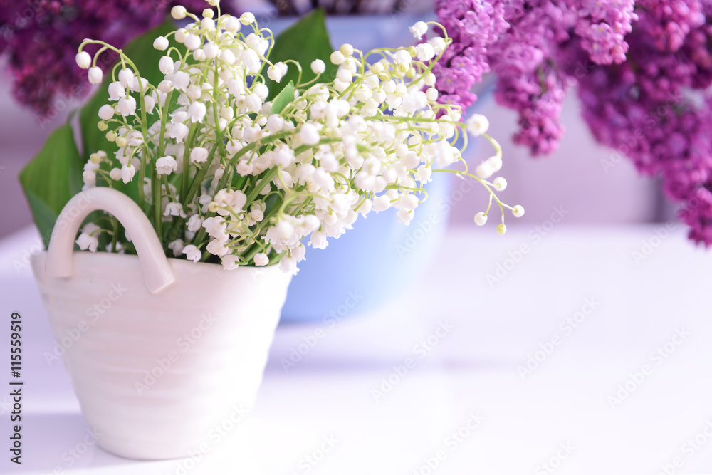 Fototapeta premium Lilac and may-lily bouquets on white table