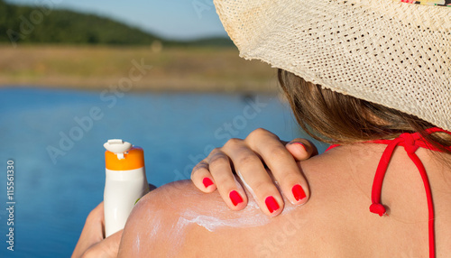 Quadro em tela Young woman putting sun lotion on summer vacation