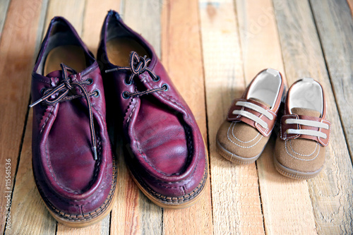 Big and small shoes on wooden background