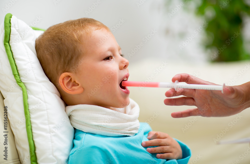 Mother giving syrup to his sick son Mother giving syrup to his sick son