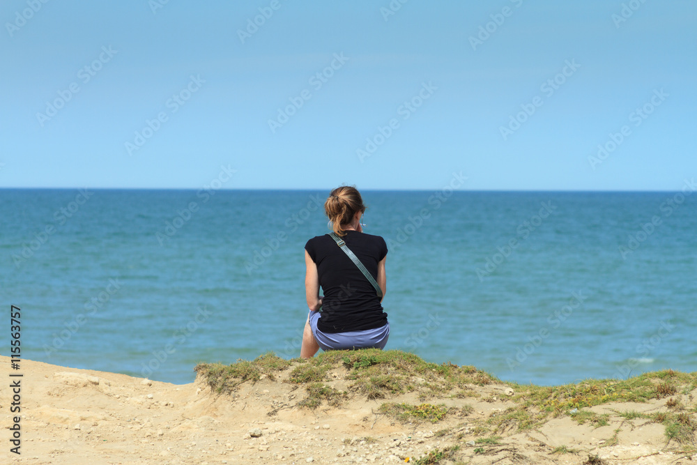 Young woman seen from behind smoking oceanfront