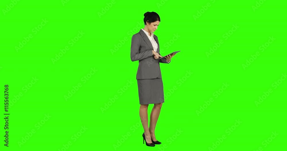 Business woman standing and using a tablet on green screen Business woman standing and using a tablet on green screen