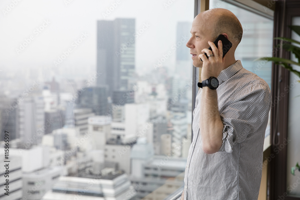 Japan, Tokyo, Shibuya, Man talking on phone and looking through window Japan, Tokyo, Shibuya, Man talking on phone and looking through window