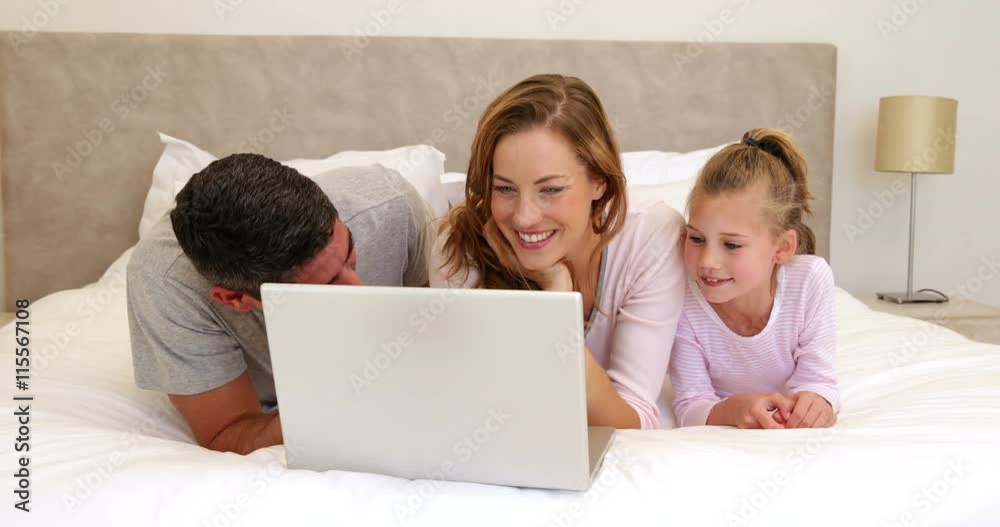 Family using laptop together on bed Family using laptop together on bed